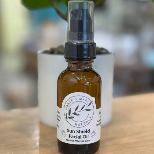 Bottle of Sun Shield Facial Oil with a blurred plant in the background